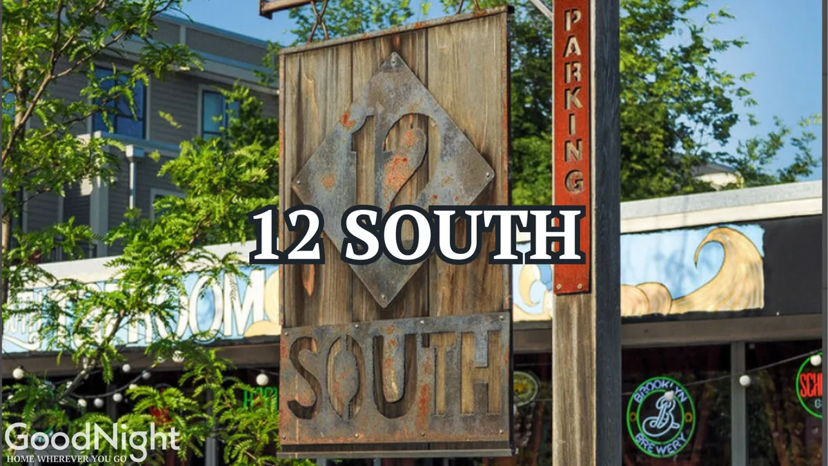 A prominent '12 SOUTH' sign is nestled among greenery, accompanied by a parking sign—hinting at both ease of parking and the lively local scene. The area is bustling with activity, surrounded by shops and restaurants, suggesting a vibrant neighborhood character just outside the door.