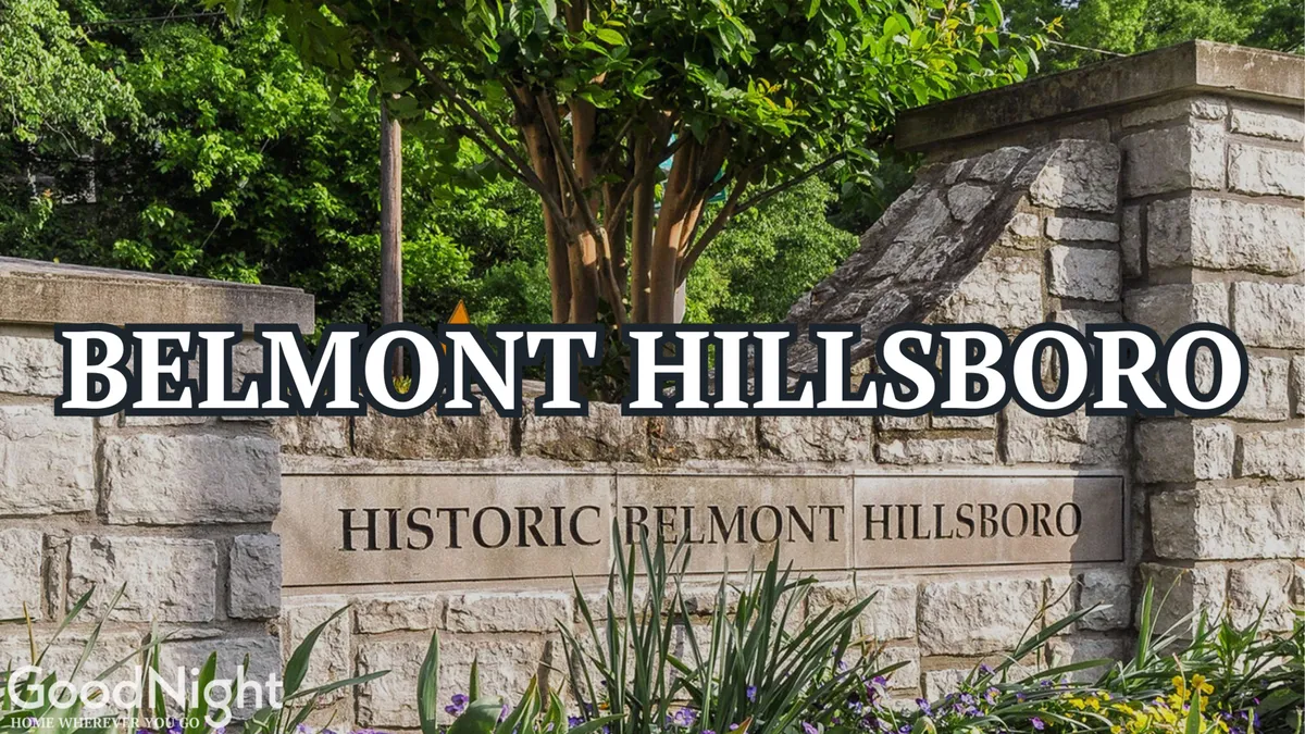 A welcoming stone sign reading 'Belmont Hillsboro' sits amid lush landscaping and a well-kept stone wall, evoking the feel of a friendly, walkable neighborhood. The scene suggests easy pedestrian access and a sense of community, ideal for parents, alumni, or prospective students visiting the area.